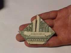 a hand holding a folded dollar bill origami