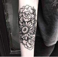 a black and white photo of a sunflower tattoo on the right arm with flowers around it