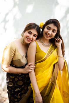 two young women in sari posing for the camera with their arms around each other