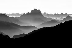 black and white photograph of mountains with fog in the air, taken from high up