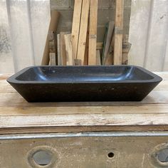 a black bowl sitting on top of a wooden table next to some wood planks