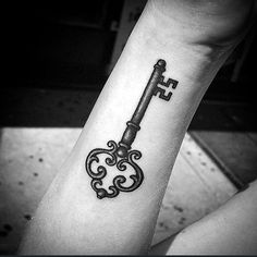 a person with a tattoo on their arm has a key tattooed on the wrist and is looking at it