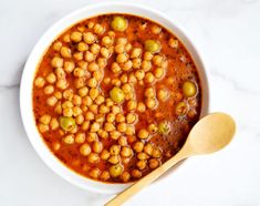 a white bowl filled with beans next to a wooden spoon