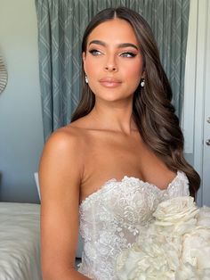 a woman in a wedding dress holding a bouquet of flowers and posing for the camera