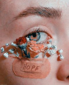 a woman with flowers in her eye and the word love spelled on her cheek behind it