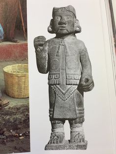 an old photo of a statue next to a basket on the ground in front of it