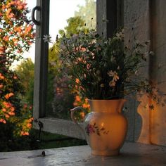 a vase filled with flowers sitting on top of a table next to an open window