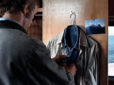 a man looking at his jacket hanging on the wall