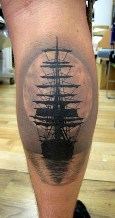 a man's leg with a black and white tattoo of a ship on it