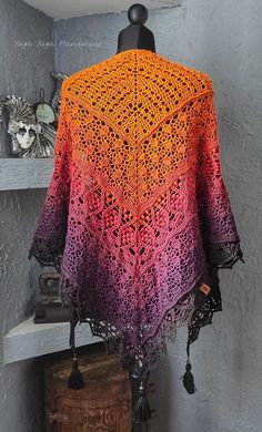 an orange and pink crocheted shawl on a mannequin