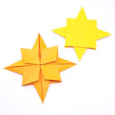 two yellow origami stars sitting next to each other on top of a white surface