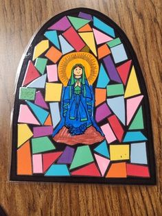 an image of the virgin mary in stained glass on a wooden table with a computer mouse