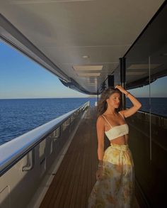 a woman standing on the deck of a boat looking at the ocean with her hand in her hair