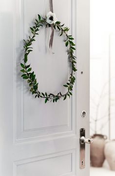 a white door with a green wreath hanging on it's side next to a phone