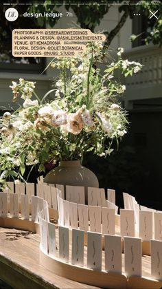 flowers in a vase sitting on top of a wooden table next to cards and envelopes