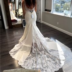 a woman in a wedding dress looking at herself in the mirror with her back to the camera