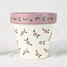 a pink and white flower pot with green leaves on it