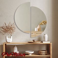 there is a mirror on the wall next to a table with bowls and vases