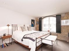 a bedroom with a large bed and brick wall behind it, along with two lamps on either side of the bed