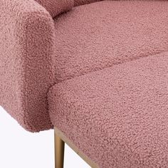 a close up of a pink couch with gold legs