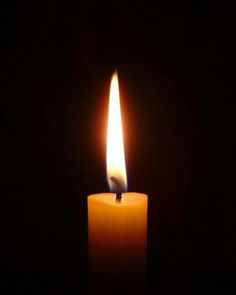 a lit candle in the dark on a black background