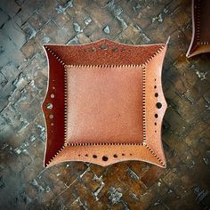 a brown leather tray sitting on top of a wooden floor