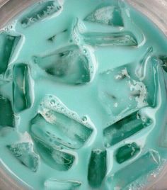 ice cubes in a blender filled with water and green liquid, top view