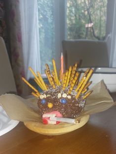 a cake with sticks sticking out of it on top of a wooden table in front of a window