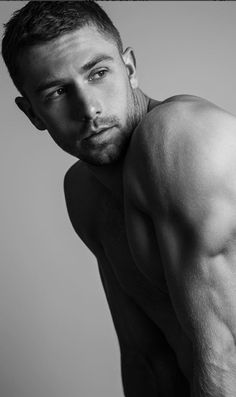 a shirtless man poses for a black and white photo