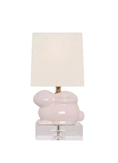 a lamp that is on top of a glass block with a white shade over it