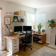 a home office with two computer screens and a fireplace