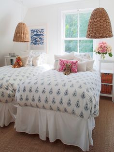 a bedroom with white bedding and pink flowers in the window sill next to it