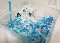 a plastic container filled with lots of blue and white beads next to a snowman