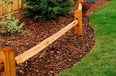 a wooden bench sitting in the middle of a garden next to a fence and bushes