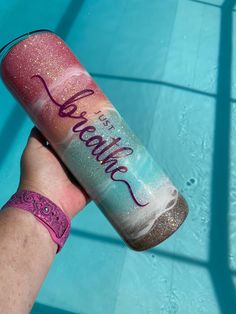 a person holding up a pink and blue tube with writing on it next to a swimming pool