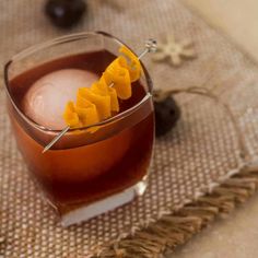 an old fashioned cocktail with orange peels on the rim and garnishes