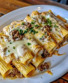 a white plate topped with pasta covered in cheese and meat sauce on top of a wooden table