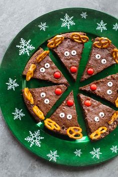 a green plate topped with slices of pizza covered in pretzels and candy eyes