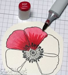 a red and black flower is next to a marker on a piece of white paper