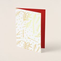 a red and white christmas card with gold foil on the front, featuring pine branches