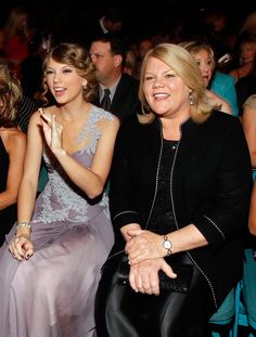 two women sitting next to each other in front of a crowd at a formal event