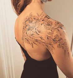 the back of a woman's shoulder with flowers and birds tattoo on her upper arm