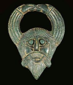 an ancient bronze mask with horns on it's head and two eyes in the center