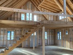 the inside of a house being built with wood framing and windows on each side of the staircase