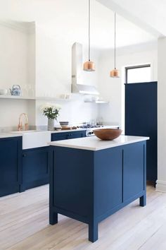 a large kitchen with blue cabinets and white counter tops, along with an island in the middle