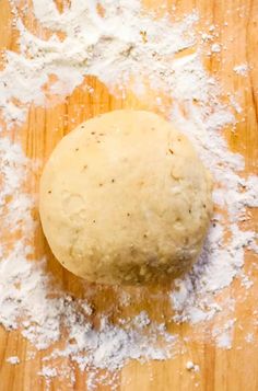 a ball of dough sitting on top of a wooden table covered in powdered sugar