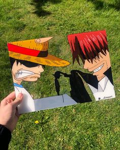 someone is holding up a cut out of one piece of anime characters in the grass