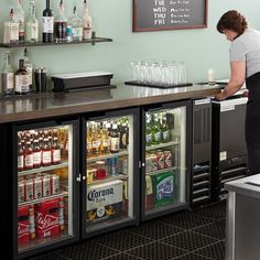 a woman is standing at the bar in front of an assortment of beverages