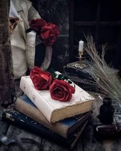 a stack of books sitting on top of each other next to a candle and some flowers