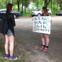 two young women holding up a sign that says go to prom